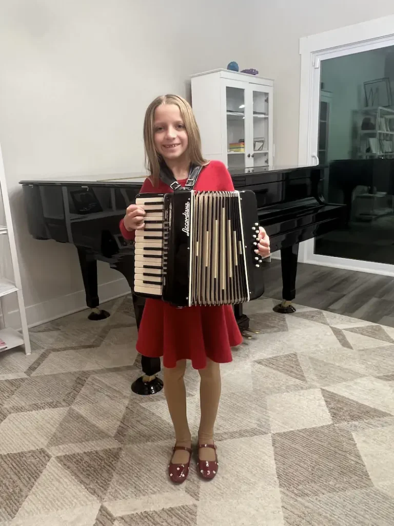 Young girl in red dress holding a black accordion