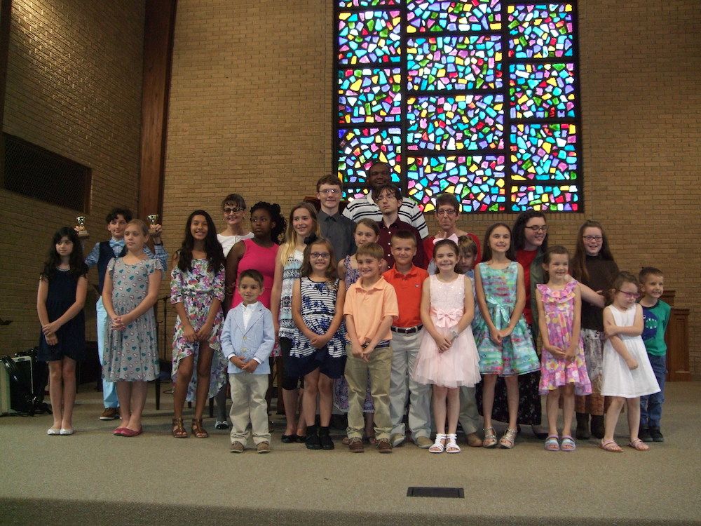 Group of children posing in church with stained glass window