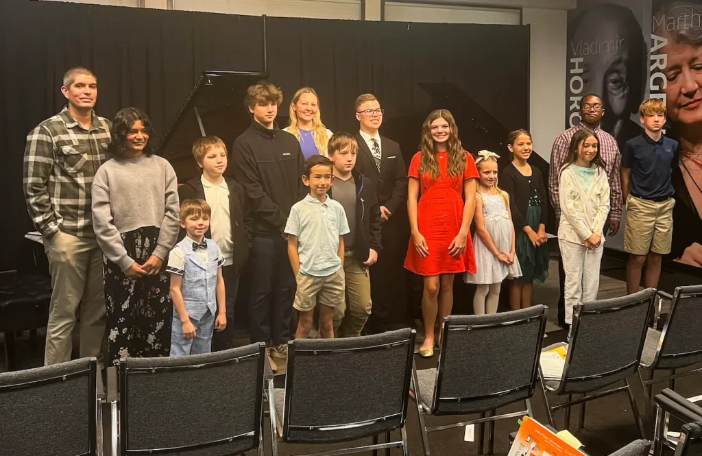 Group of children and adults posing after piano recital