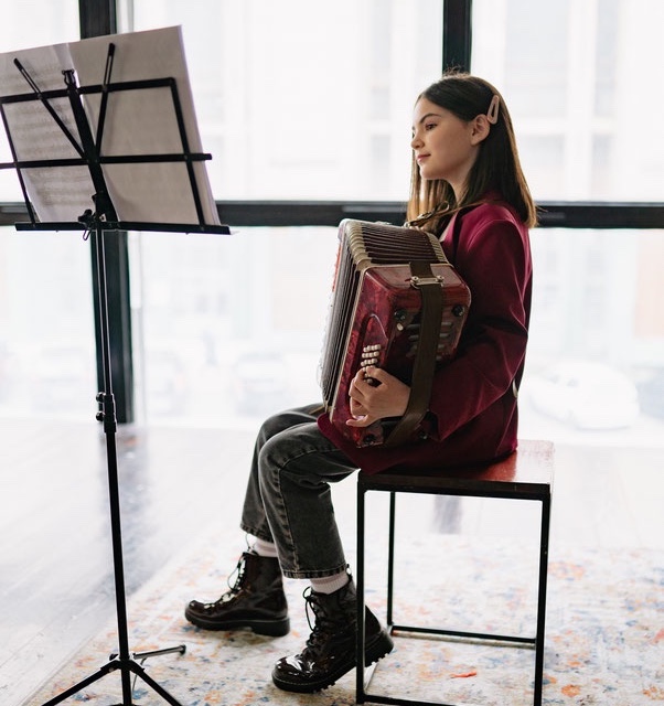 Young girl playing accordion while reading sheet music