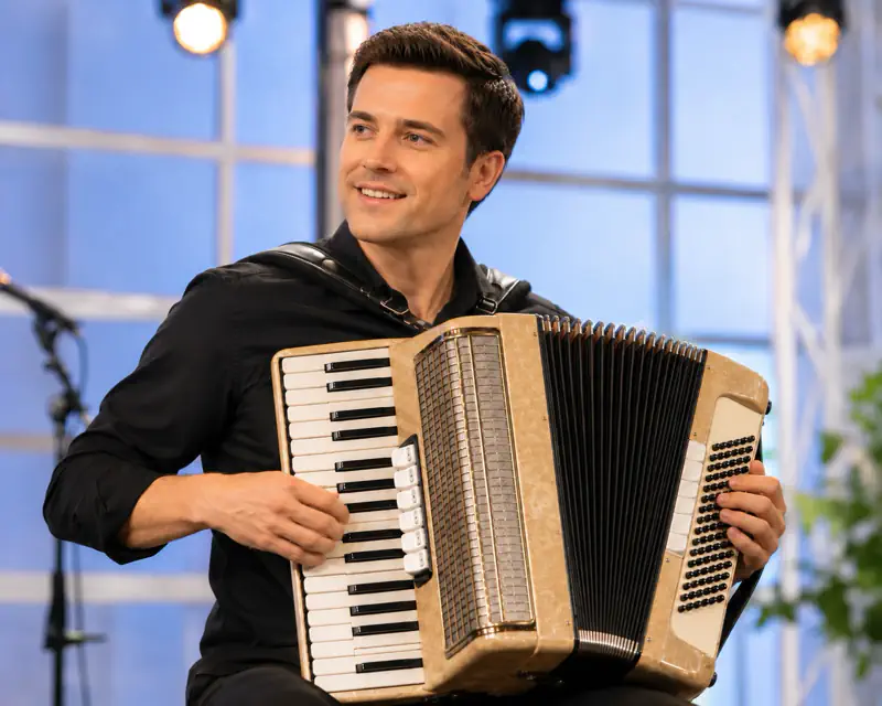 Smiling man playing accordion on a lit stage
