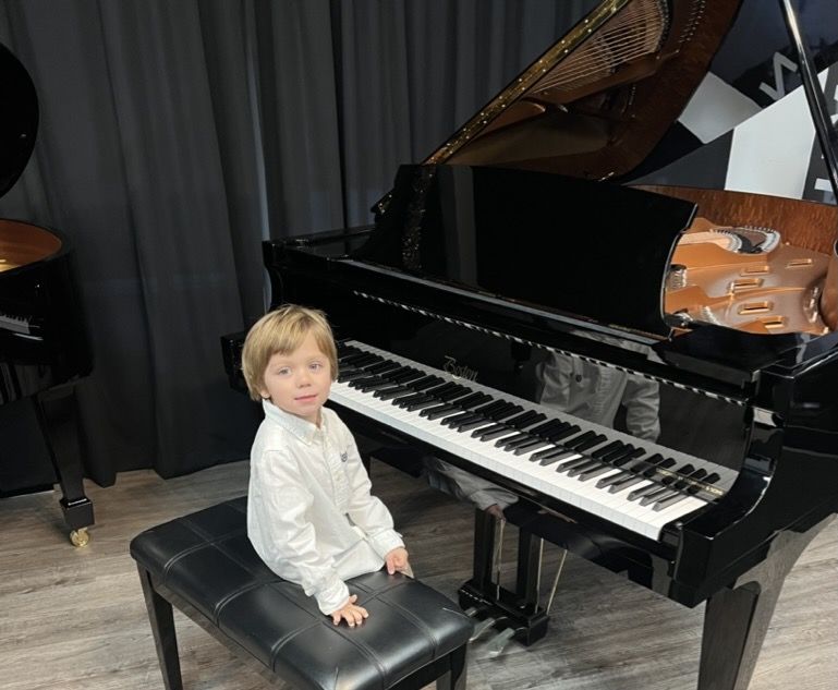 Young boy sitting at a shiny black grand piano