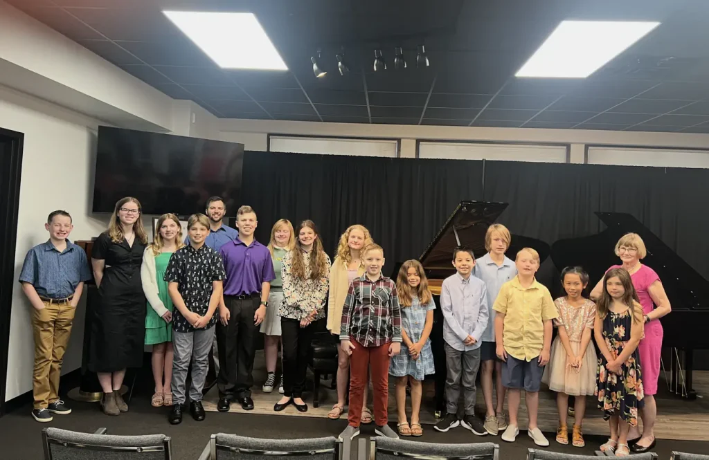 Group of children and adults posing at piano recital