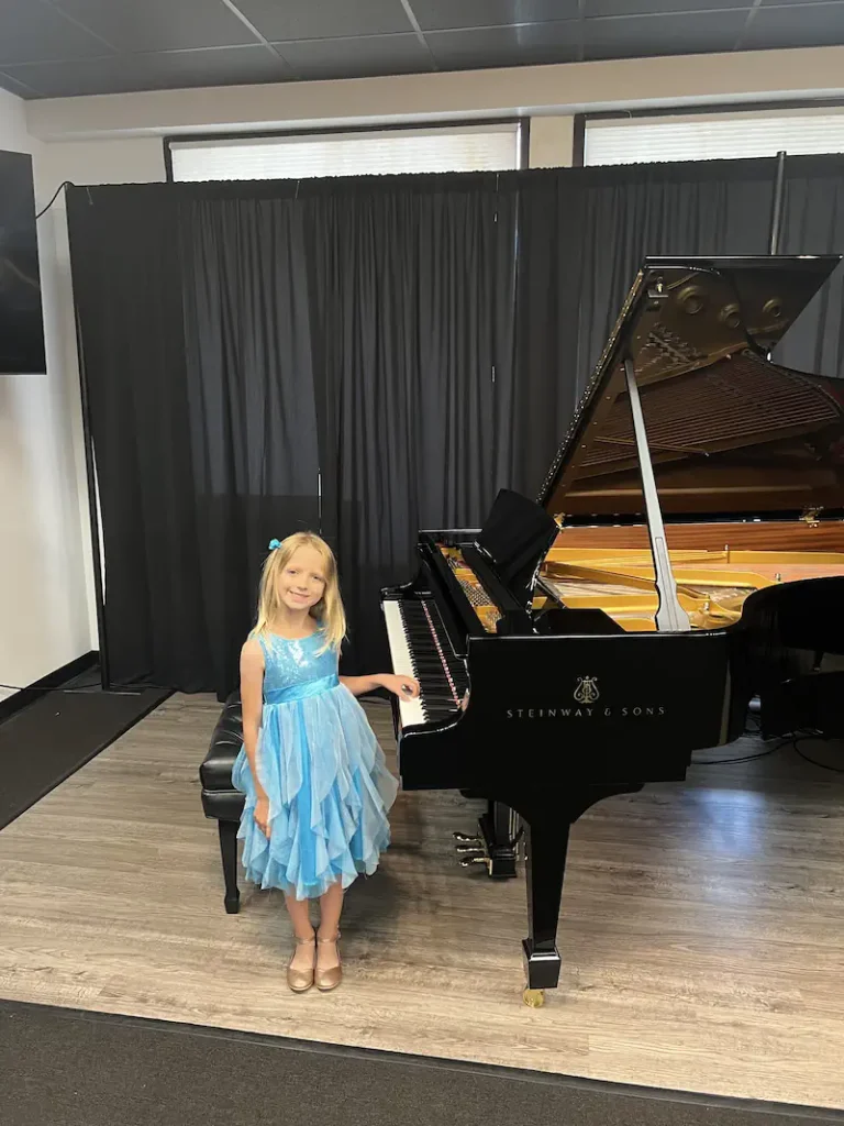 Young girl in blue dress posing at Steinway grand piano
