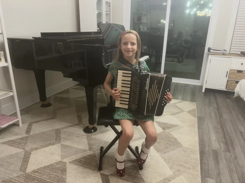 Young girl smiling while holding an accordion indoors
