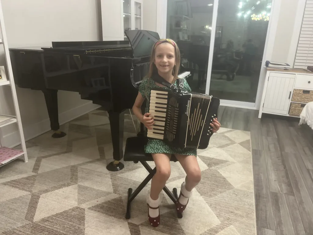 Young girl smiling while holding an accordion indoors